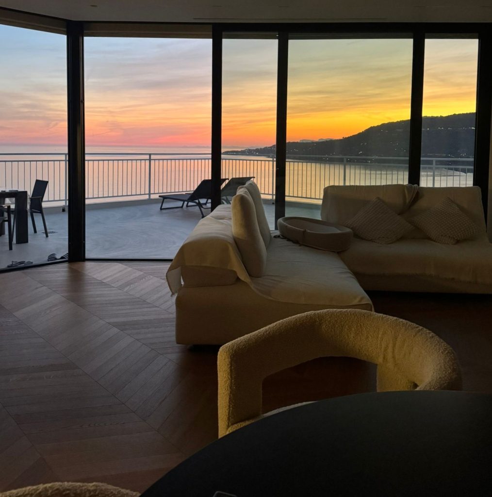 Tramonto sul golfo di Sanremo visto attraverso la vetrata d'angolo minimale dell'attico panoramico