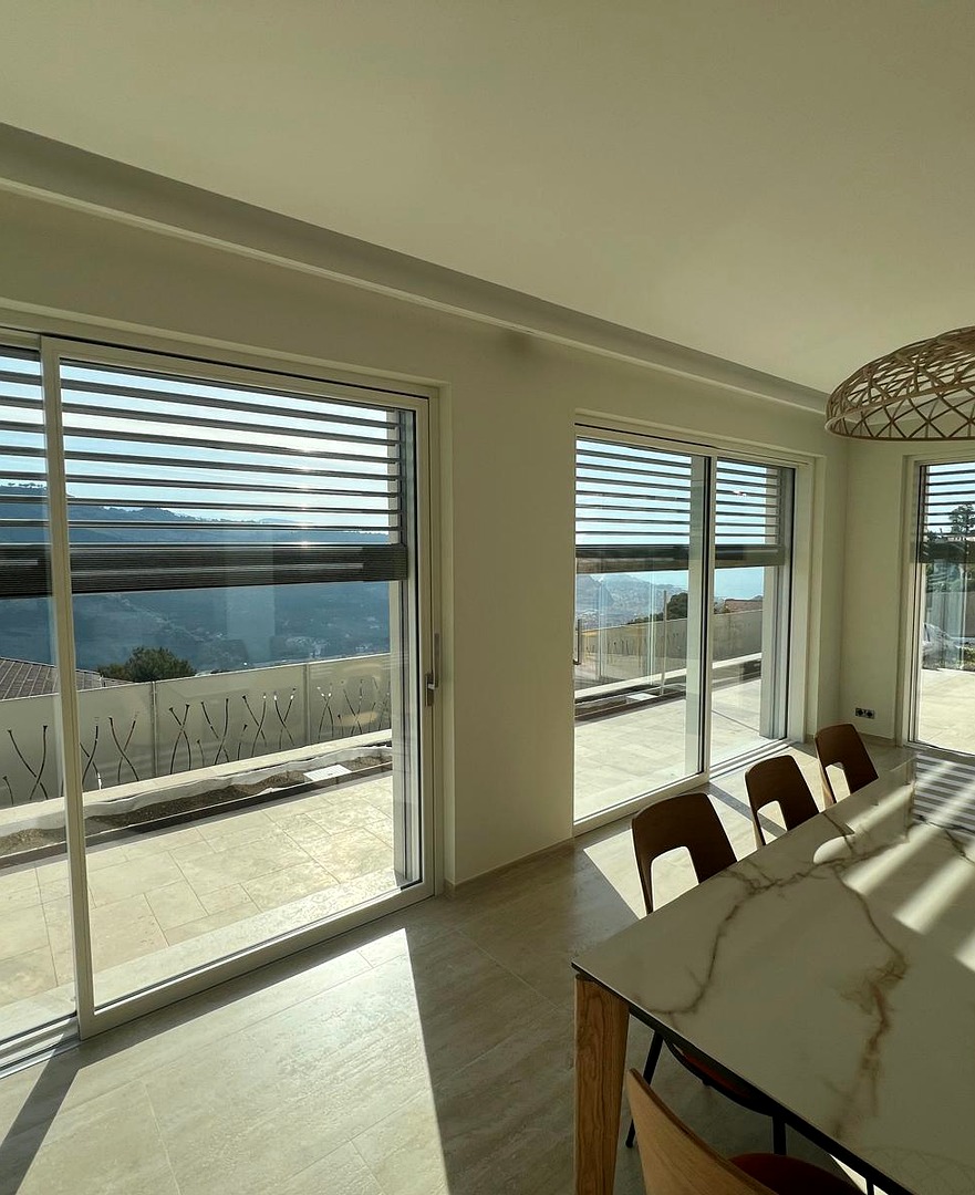 Interni con ampie vetrate scorrevoli in legno e vista sul mare, villa a Sanremo
